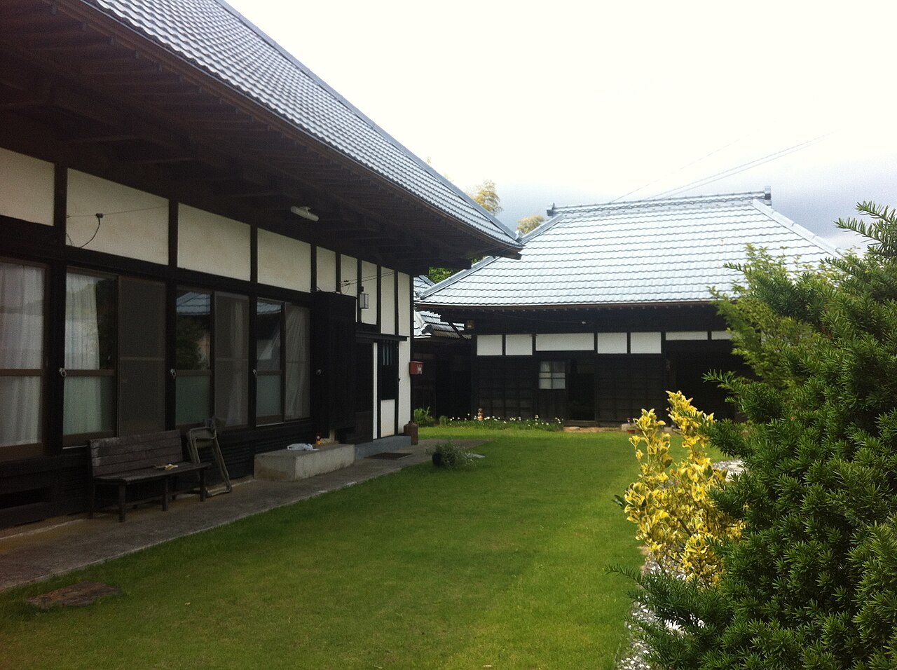 Traditional Japanese farmhouse with tiled roofs and a grassy courtyard in Okugame, Chiba.